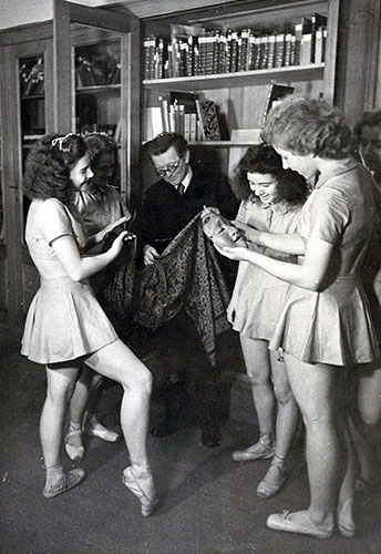 Februar 1943: Die letzte Aufnahme des Deutschen Tanzarchivs in Berlin vor dem Totalverlust bei einem britischen Luftangriff. Gestelltes Foto für eine offizielle Verwendung, Fritz Böhme zeigt den Tanzschülerinnen in der Bibliothek einen javanischen Sarong und eine japanische Maske.
